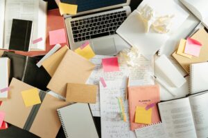 An IT Administrator's untidy desk with a laptop and lots of post-it notes